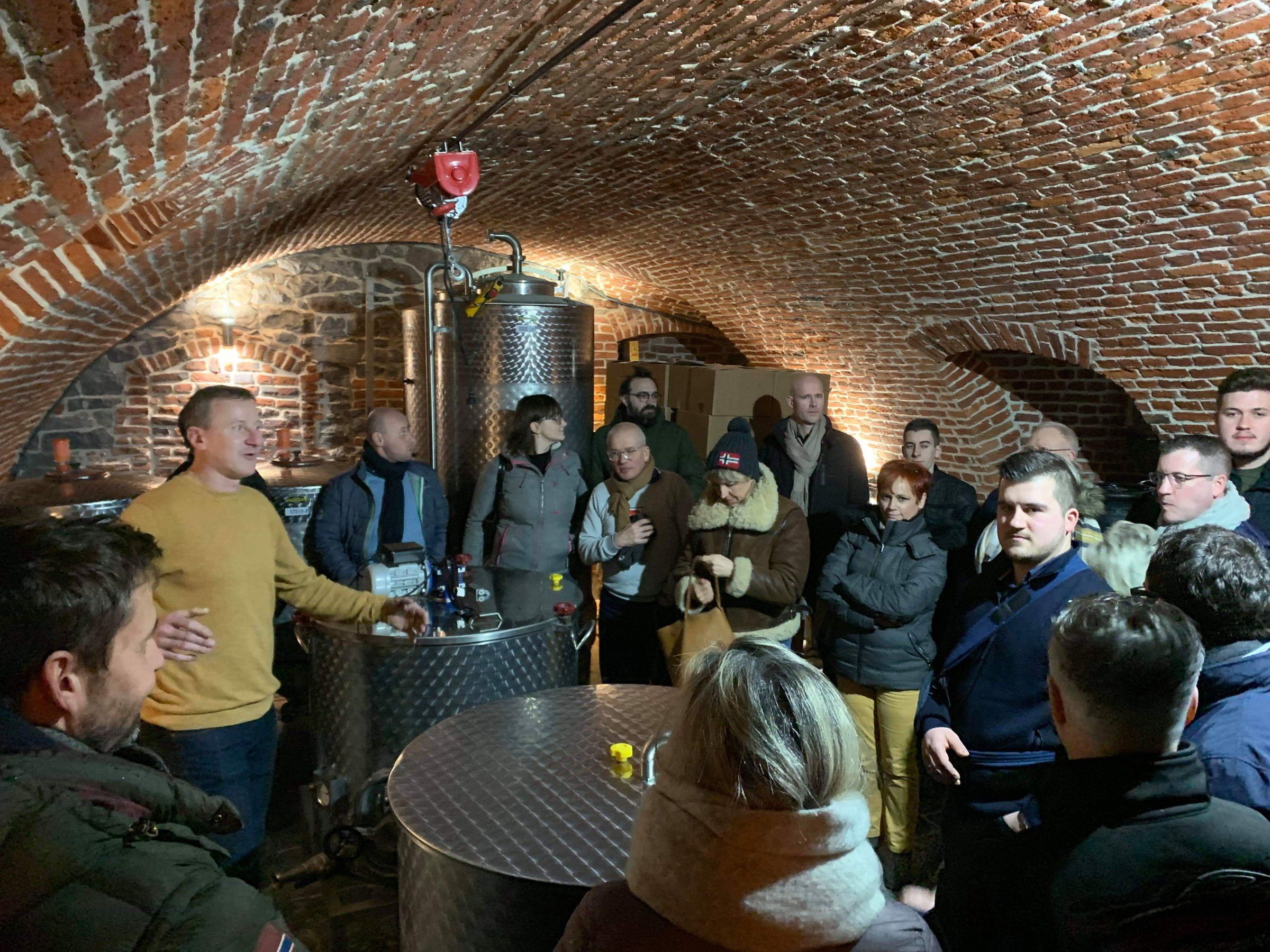 Visite commentée d’un groupe dans les caves voûtées en briques de la brasserie